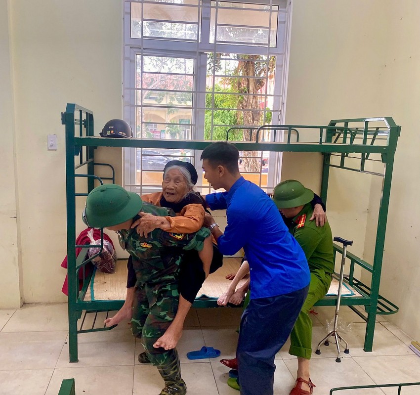 Một cụ bà được  lực lượng Công anđưa đến nơi trú bão an toàn.