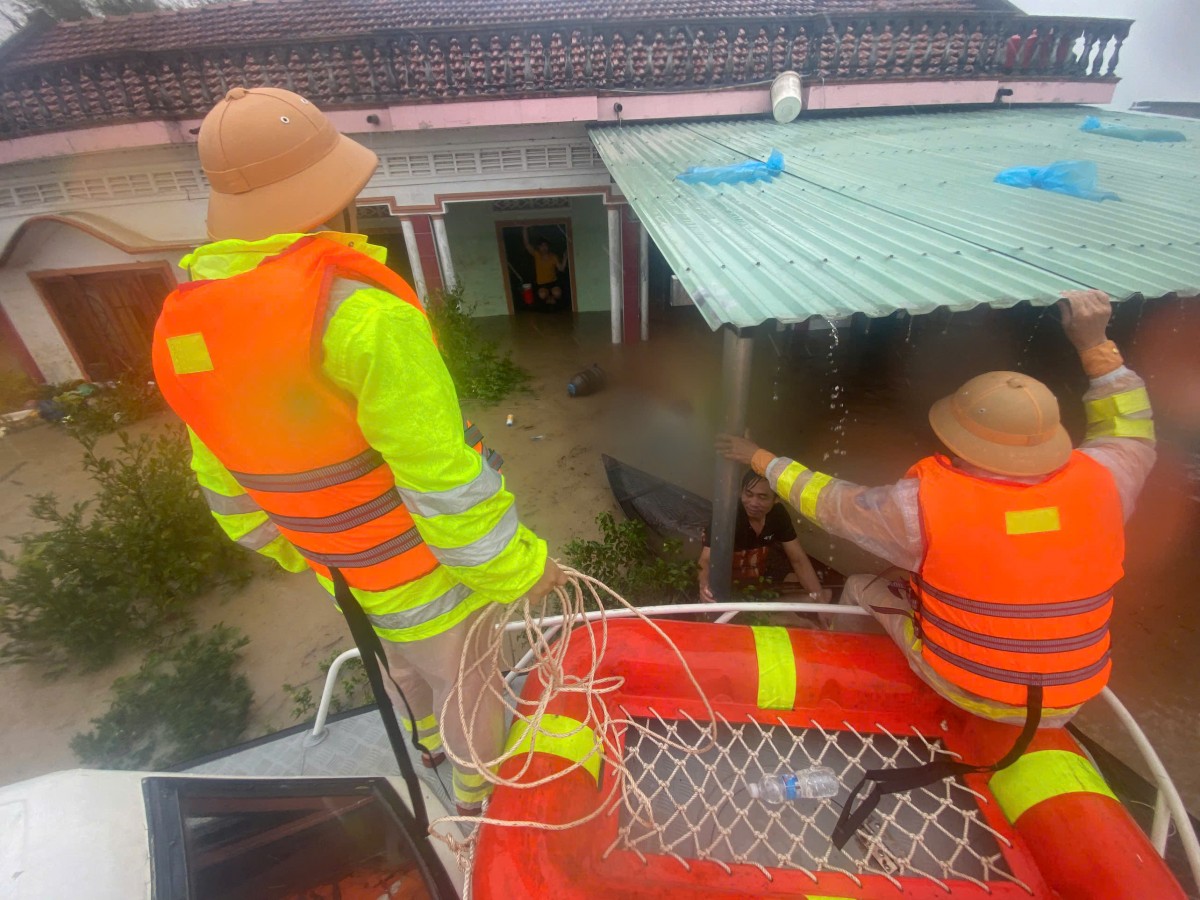 Lực lượng cứu hộ hỗ trợ người dân mắc kẹt trong vùng ngập lụt, đưa thuyền tiếp cận mái nhà ứng cứu người dân trong mưa lớn.