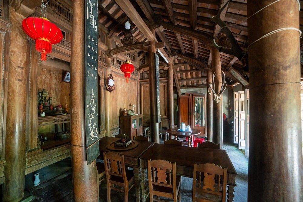 Không gian nội thất nhà rường gỗ mít tại Làng cổ Lộc Yên với cột gỗ, bàn thờ và hoa văn chạm khắc tinh xảo.