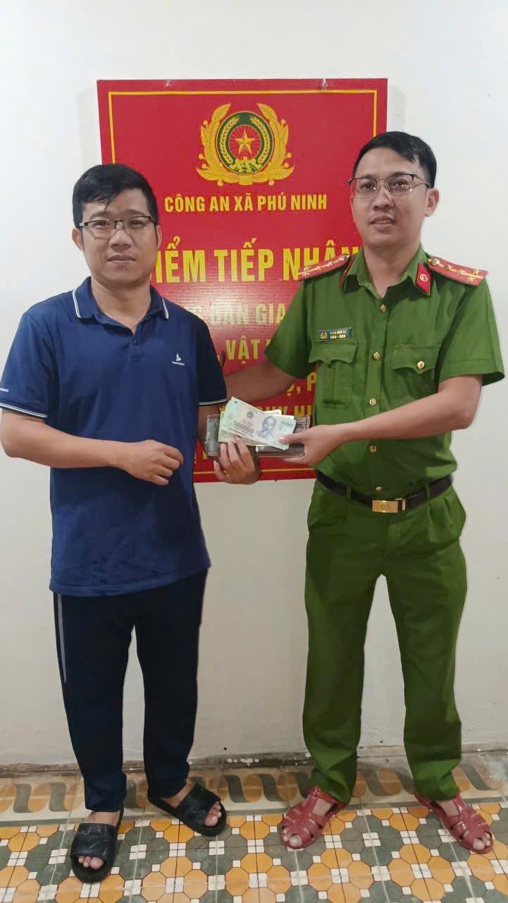 Anh Nguyễn Đại Vinh (bên trái) bàn giao chiếc ví nhặt được cho Công an xã Phú Ninh để xác minh, trao trả cho người đánh rơi. Ảnh: Công an xã Phú Ninh