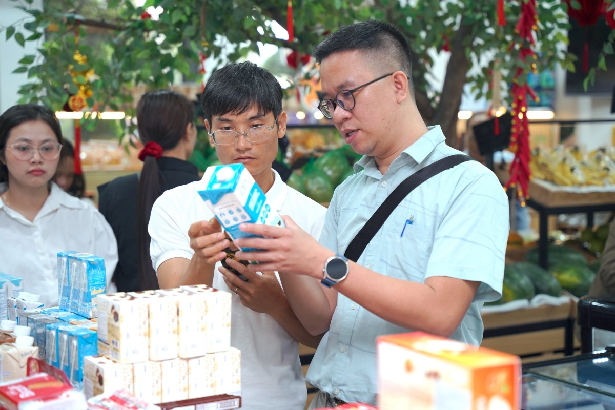 Các học viên quan sát tem truy xuất nguồn gốc, logo chứng nhận và thông tin bao bì tại cửa hàng bán sản phẩm hữu cơ.