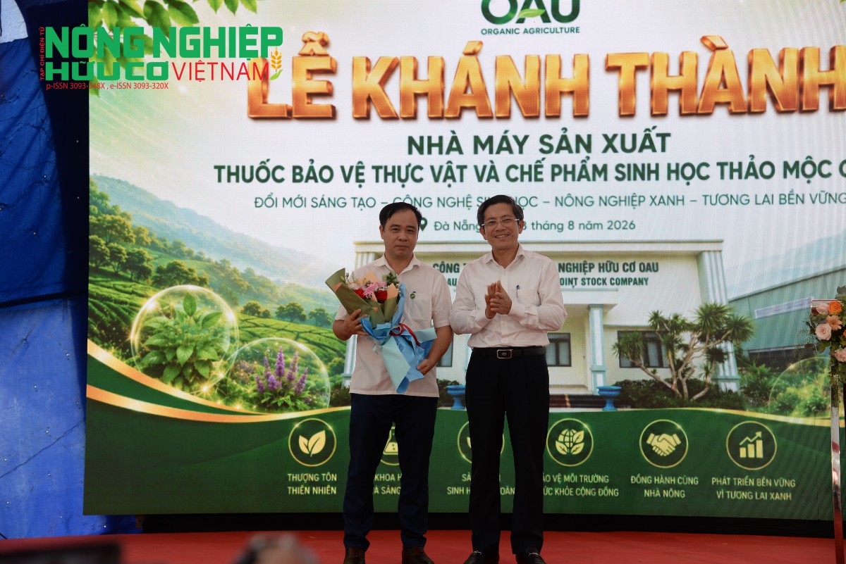 Đồng chí Trần Nam Hưng, Phó Chủ tịch UBND thành phố Đà Nẵng (bên phải) tặng hoa chúc mừng đại diện Công ty Cổ phần Nông nghiệp Hữu cơ OAU (bên trái) nhân dịp khánh thành nhà máy.