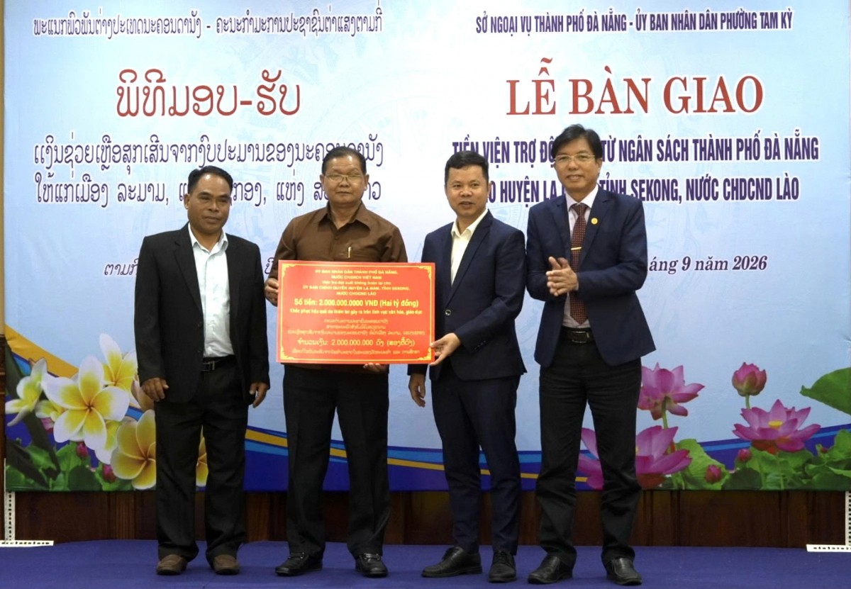 Đại diện lãnh đạo Sở Ngoại vụ TP. Đà Nẵng và UBND phường Tam Kỳ trao biển tượng trưng khoản viện trợ 2 tỷ đồng cho đại diện Ủy ban Chính quyền huyện Lạ Màm (tỉnh Sê Kông, Lào).