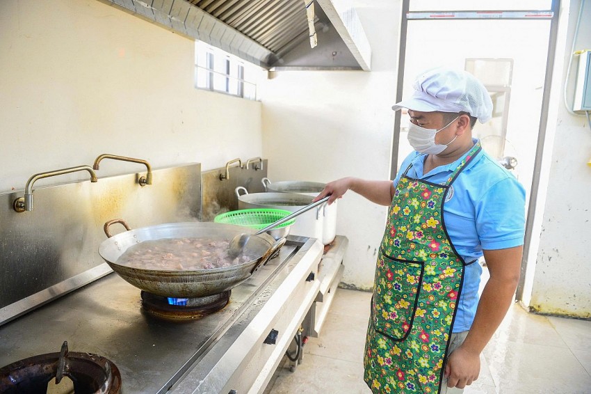 Anh Lê Văn Thành, nhân viên cấp dưỡng của trường đang miệt mãi công việc nấu ăn phục vụ các em học sinh thân yêu tại trường Tiểu học và THCS Yên Khương. 